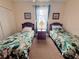 Bright bedroom with two twin beds, tropical bedding, and a window with a view at 13427 Blue Heron Dr # 2-1401, Orlando, FL 32821