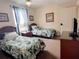Cozy bedroom featuring two twin beds with tropical patterned bedding and a scenic view from the window at 13427 Blue Heron Dr # 2-1401, Orlando, FL 32821
