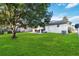 Great view of the spacious backyard featuring green grass, a large tree, and an outdoor patio at 16603 Corner Lake Dr, Orlando, FL 32820
