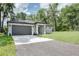 One-story home with a gray exterior, dark roof, and a paved driveway leading to an attached two-car garage at 1868 14Th St, Orange City, FL 32763