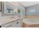 Bright bathroom features a large soaking tub with a window, and a marble countertop vanity with ample storage space at 19630 County Road 455, Clermont, FL 34715