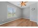 Bright bedroom featuring wood floors, a ceiling fan, and a window with scenic outdoor views at 19630 County Road 455, Clermont, FL 34715