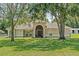 Spacious home featuring arched entryway, circular windows, and mature trees at 19630 County Road 455, Clermont, FL 34715