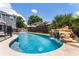 Gorgeous pool with a rock waterfall feature, complemented by lush landscaping and a safety fence at 207 Via Tuscany Loop, Lake Mary, FL 32746