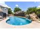 Beautiful pool with a rock waterfall feature, surrounded by lush landscaping and a secure safety fence at 207 Via Tuscany Loop, Lake Mary, FL 32746