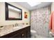 Well-lit bathroom featuring a granite vanity, framed mirror, and shower with floral curtain at 2678 Wilmhurst Rd, Deland, FL 32720