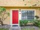 Charming home featuring a vibrant red front door, complemented by lush landscaping and a window at 3247 Forest Oaks Ct # 116, Winter Park, FL 32792