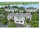 Aerial view features colorful townhomes, mature landscaping, community pool, and lake in the distance at 3280 Soho St # 306, Orlando, FL 32835