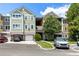 Multi-story condo building with attached garages and colorful facade, surrounded by landscaping and parking area at 3280 Soho St # 306, Orlando, FL 32835