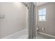 Bright bathroom featuring tub with shower, window and grey tile flooring at 3990 Bannock Ave, Tavares, FL 32778