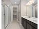 Well-lit bathroom with double sinks, dark wood cabinetry, large mirror, glass shower, and walk-in closet at 3990 Bannock Ave, Tavares, FL 32778