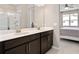 Bathroom featuring a double sink vanity, large mirror, and glass enclosed shower with natural light at 3990 Bannock Ave, Tavares, FL 32778