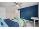 This bedroom features a ceiling fan, gray tile floors, blue accent wall, and a bed with blue comforter at 3990 Bannock Ave, Tavares, FL 32778