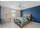 This bedroom has a ceiling fan, blue accent wall, gray tile floors, and a window for natural light at 3990 Bannock Ave, Tavares, FL 32778