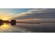 Beautiful waterfront view with a dock and building on the water as the sun sets over the horizon at 4471 Treasure Cay Rd, Tavares, FL 32778