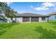 Spacious backyard with green lawn, screened patio, and view of the home's exterior at 4940 Tennessee Lake Dr, Auburndale, FL 33823