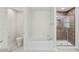 Bright bathroom featuring a soaking tub, glass-enclosed shower with brown wood-look tile and white tiled flooring at 4940 Tennessee Lake Dr, Auburndale, FL 33823