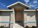Inviting front porch featuring decorative columns, neutral tones, and an eye-catching peach colored front door at 56 Redwood Rd, Ocala, FL 34472