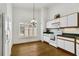 Eat-in kitchen featuring white cabinets, wood-look flooring, a window with plantation shutters, and a modern lighting fixture at 561 Vineyard Way, Poinciana, FL 34759