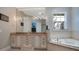 Bathroom featuring double vanity with granite countertops, tub, and tv at 5708 Emerington Cres, Orlando, FL 32819