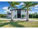 View of a modern two-story home with manicured lawn, palm trees, and a patterned driveway at 5708 Emerington Cres, Orlando, FL 32819