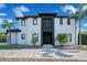 View of a modern two-story home with manicured lawn, palm trees, and a patterned driveway at 5708 Emerington Cres, Orlando, FL 32819