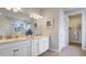 Bathroom vanity with double sinks, granite countertops, white cabinetry, and a walk-in closet at 7206 Nottingham Reel Ct, St Cloud, FL 34773