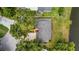Aerial view of a charming single-story home with a well-maintained yard, mature trees, and a peaceful pond nearby at 7237 Woodville Cres, Orlando, FL 32819