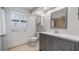 Well-lit bathroom featuring a gray vanity, a toilet, and window with white shutters at 7237 Woodville Cres, Orlando, FL 32819