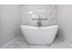 Elegant freestanding bathtub with marble tile backdrop and hexagon tile flooring at 7237 Woodville Cres, Orlando, FL 32819