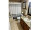 Bathroom featuring tile floors, granite countertop and a shower/tub combination with striped curtain at 734 La Costa St, Minneola, FL 34715