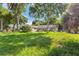 A grassy front yard with mature trees framing a single-story home, and a car in the driveway at 1511 Center Ave, Holly Hill, FL 32117