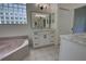 Bathroom featuring double marble countertop sinks, a soaking tub, and a glass block window at 1679 Shadowmoss Cir, Lake Mary, FL 32746