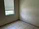 Bedroom features neutral walls, tile flooring, baseboards, and natural light from a window at 2149 Mallard Creek Cir, Kissimmee, FL 34743