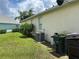 Side view of the home's exterior showing the central air conditioning unit, trash receptacles, and trimmed hedges at 2149 Mallard Creek Cir, Kissimmee, FL 34743