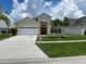 Charming home with a well-maintained lawn, palm trees, a two-car garage, and a vibrant red front door at 2149 Mallard Creek Cir, Kissimmee, FL 34743