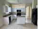 Well-lit kitchen featuring white cabinetry, an island, granite countertops, and black appliances at 2149 Mallard Creek Cir, Kissimmee, FL 34743