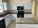 Well-lit kitchen features granite countertops, white cabinetry and a black appliance package at 2149 Mallard Creek Cir, Kissimmee, FL 34743