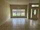 Bright living room featuring tile flooring, natural light from large window, and an attractive front door at 2149 Mallard Creek Cir, Kissimmee, FL 34743