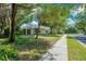 View of the backyard from the sidewalk surrounded by lush greenery and mature trees at 216 Homestretch Blvd, Deland, FL 32724