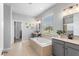 Main bathroom features a soaking tub, dual vanities, tile flooring, and a large window at 2781 Sand Oak Loop, Apopka, FL 32712