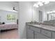 Bathroom featuring granite countertops, gray cabinetry, mirror, and a bedroom view at 3984 Mayhill Loop, Eustis, FL 32736