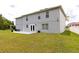 View of the home's back exterior with a grassy lawn, patio, and lush greenery for outdoor enjoyment at 4064 Sunny Day Way, Kissimmee, FL 34744
