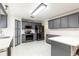 Open kitchen featuring gray cabinets, stainless steel appliances, white countertops, and white tile flooring at 4064 Sunny Day Way, Kissimmee, FL 34744