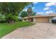 Exterior shot of a one-story home with a tile roof, lawn, and a driveway leading to an attached garage at 5237 Gateway Ave, Orlando, FL 32821