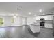 A living room and kitchen features wood-style flooring, white cabinets, and stainless steel appliances at 667 Bay Leaf Dr, Kissimmee, FL 34759