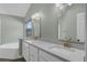 Bathroom with a double sink vanity, quartz countertop, gold hardware, and a large soaking tub at 762 Lake Como Dr, Lake Mary, FL 32746