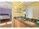 Well-lit bathroom with double sinks, granite counters, and a view into an adjacent bedroom at 9128 Phillips Grove Ter, Orlando, FL 32836