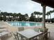 Community pool surrounded by palm trees and lounge chairs, with patio seating in the foreground at 922 Suffolk Pl, Davenport, FL 33896