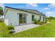 A backyard with well-manicured lawn, brick patio, sliding glass doors, and tropical landscaping at 1006 Linkside Ct, Apopka, FL 32712